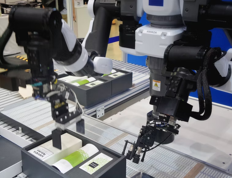 Industrial automation robotic arms hovered over boxes of products